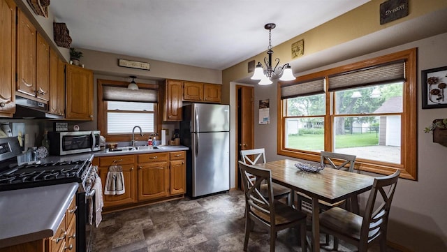 132 N Eagle St, Oshkosh, WI 54902 - kitchen featuring appliances with stainless steel finishes, brown cabinetry, a chandelier, and plenty of natural light