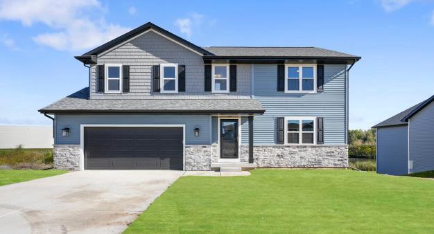 N6220 Blarney Stone Dr Unit 53, Albany, WI 53520 - view of front of home with stone siding, a front yard, an attached garage, and driveway
