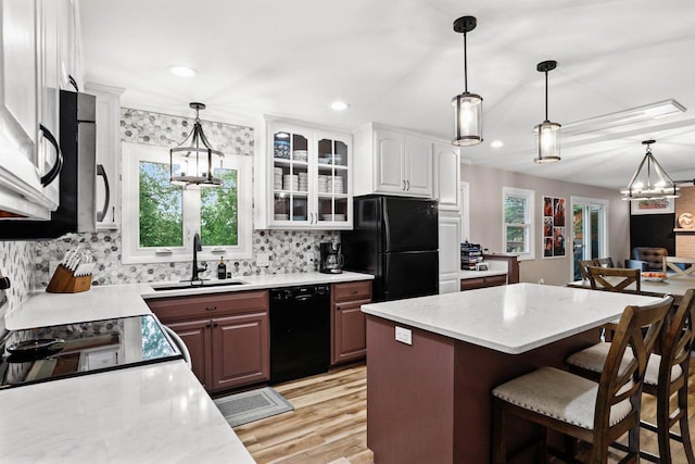 521 Maunesha Dr, Marshall, WI 53559 - kitchen with black appliances, a breakfast bar area, backsplash, light wood-style flooring, and glass insert cabinets