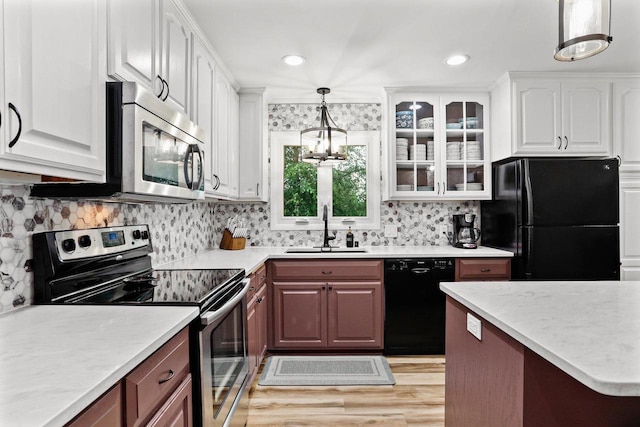 521 Maunesha Dr, Marshall, WI 53559 - kitchen featuring black appliances, light countertops, glass insert cabinets, pendant lighting, and light wood-type flooring