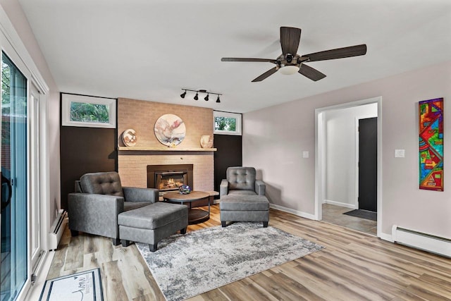 521 Maunesha Dr, Marshall, WI 53559 - living room with wood finished floors, healthy amount of natural light, a baseboard radiator, and a fireplace