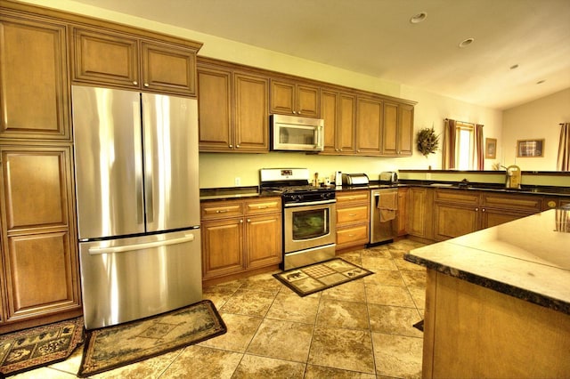 W1387 W Post Rd, Genoa City, WI 53128 - kitchen with appliances with stainless steel finishes, brown cabinets, dark countertops, and lofted ceiling