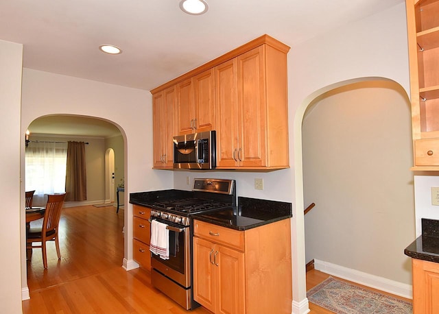 2744 N Lefeber Ave, Wauwatosa, WI 53210 - kitchen featuring stainless steel appliances, arched walkways, light wood-type flooring, recessed lighting, and dark stone countertops