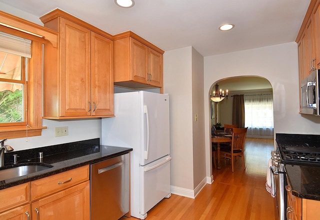 2744 N Lefeber Ave, Wauwatosa, WI 53210 - kitchen featuring stainless steel appliances, light wood finished floors, arched walkways, dark stone counters, and recessed lighting