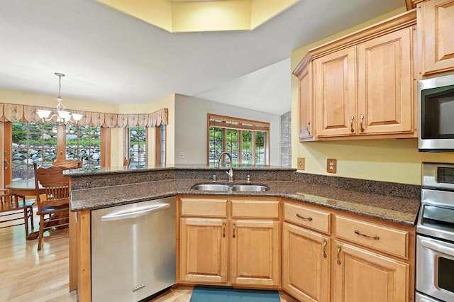 520 Bayberry Ln, Slinger, WI 53086 - kitchen featuring stainless steel appliances, a peninsula, dark stone counters, a chandelier, and decorative light fixtures