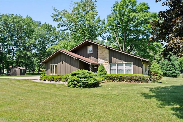 1075 E Murray Ln, Hubertus, WI 53033 - view of front of home with a shed, a front yard, board and batten siding, and stone siding