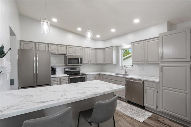 615 N Peach Ave, Marshfield, WI 54449 - kitchen featuring appliances with stainless steel finishes, gray cabinets, a breakfast bar, dark wood-style flooring, and decorative light fixtures