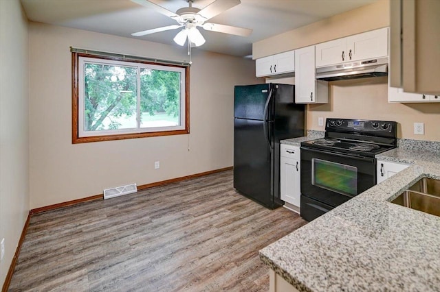 5716 Sauk Ln, Mcfarland, WI 53558 - kitchen with under cabinet range hood, black appliances, light wood finished floors, white cabinetry, and light stone counters