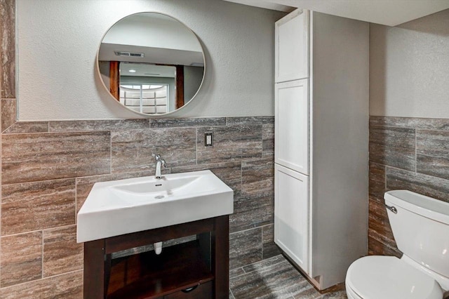 5716 Sauk Ln, Mcfarland, WI 53558 - bathroom featuring tile walls, vanity, and a wainscoted wall