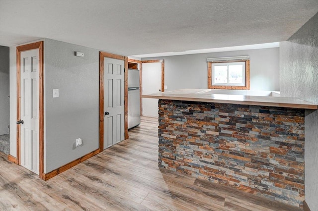5716 Sauk Ln, Mcfarland, WI 53558 - kitchen featuring light wood-style floors, freestanding refrigerator, a textured wall, and a textured ceiling