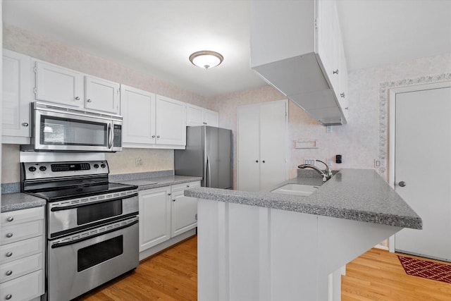 36 Stonewood Ct Unit 36, Wind Point, WI 53402 - kitchen featuring stainless steel appliances, wallpapered walls, a peninsula, light wood-style floors, and white cabinets