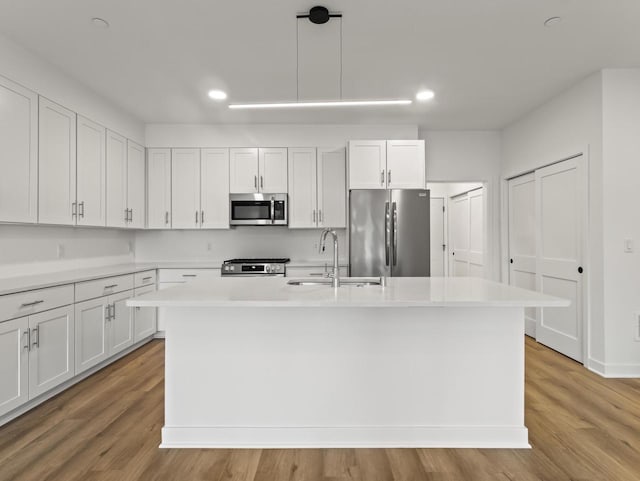 9352 S Alder Pl Unit 105, Oak Creek, WI 53154 - kitchen with stainless steel appliances, a center island with sink, light countertops, white cabinetry, and light wood-style floors