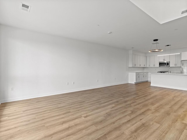 9352 S Alder Pl Unit 105, Oak Creek, WI 53154 - unfurnished living room with baseboards and light wood-style flooring