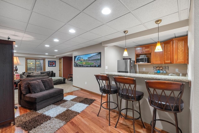 1948 Field Cliffe Dr, Richfield, WI 53076 - kitchen featuring appliances with stainless steel finishes, light wood finished floors, a peninsula, brown cabinetry, and a kitchen bar