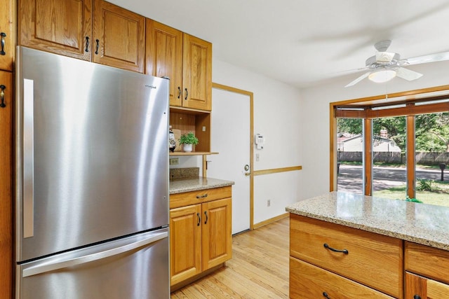 2806 Mckenna Blvd, Madison, WI 53719 - kitchen featuring freestanding refrigerator, light wood-style flooring, ceiling fan, light stone countertops, and brown cabinetry