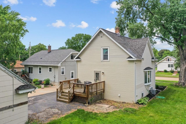 911 W Bent Ave, Oshkosh, WI 54901 - back of house with roof with shingles, a chimney, a yard, and a deck