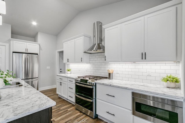 1152 Prairie View Dr, Waunakee, WI 53597 - kitchen with wall chimney range hood, stainless steel appliances, lofted ceiling, white cabinets, and tasteful backsplash