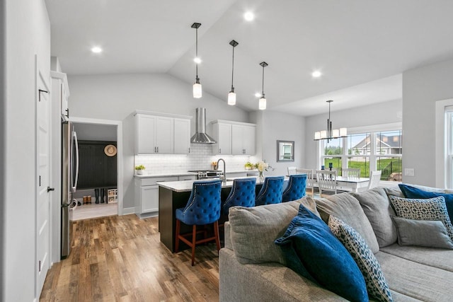 1152 Prairie View Dr, Waunakee, WI 53597 - kitchen featuring open floor plan, wall chimney exhaust hood, light countertops, a breakfast bar, and tasteful backsplash