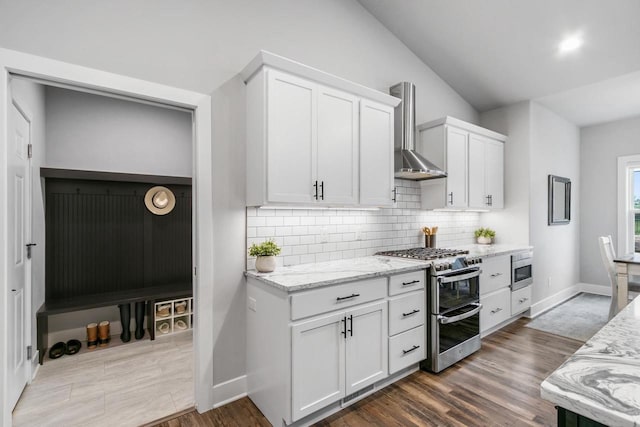 1152 Prairie View Dr, Waunakee, WI 53597 - kitchen with appliances with stainless steel finishes, wall chimney range hood, backsplash, dark wood finished floors, and light stone counters