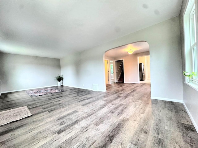 229 Bacon Ave, Oshkosh, WI 54901 - unfurnished living room featuring arched walkways, wood finished floors, and stairway