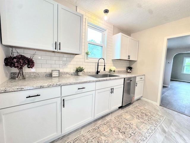 229 Bacon Ave, Oshkosh, WI 54901 - kitchen with dishwasher, backsplash, white cabinets, arched walkways, and a textured ceiling
