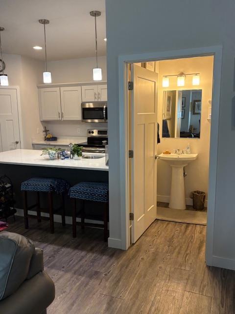 1965 N Windsor Ave, Cottage Grove, WI 53527 - kitchen featuring appliances with stainless steel finishes, wood finished floors, a breakfast bar, light countertops, and white cabinets