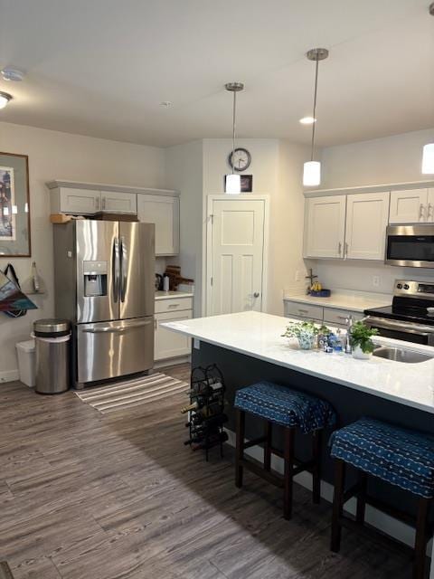 1965 N Windsor Ave, Cottage Grove, WI 53527 - kitchen featuring stainless steel appliances, light countertops, a breakfast bar area, dark wood-type flooring, and white cabinets