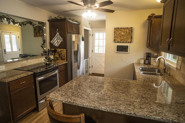 2563 S 91st St, West Allis, WI 53227 - kitchen featuring stainless steel appliances, a peninsula, dark brown cabinetry, and stone countertops
