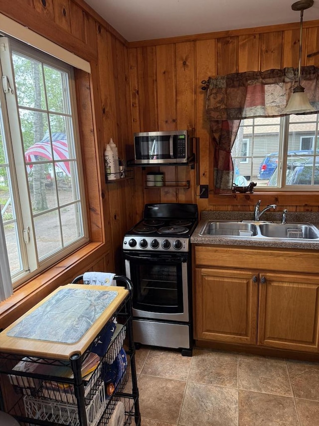 W6020 Northern Lights Cir Unit 7, Tomahawk, WI 54487 - kitchen with appliances with stainless steel finishes, brown cabinets, wooden walls, decorative light fixtures, and dark countertops
