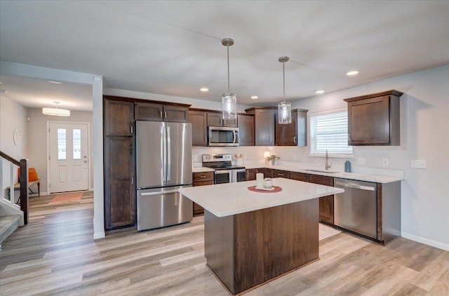 615 Prospect Rd, Waunakee, WI 53597 - kitchen with stainless steel appliances, dark brown cabinets, light wood-style floors, a kitchen island, and light countertops