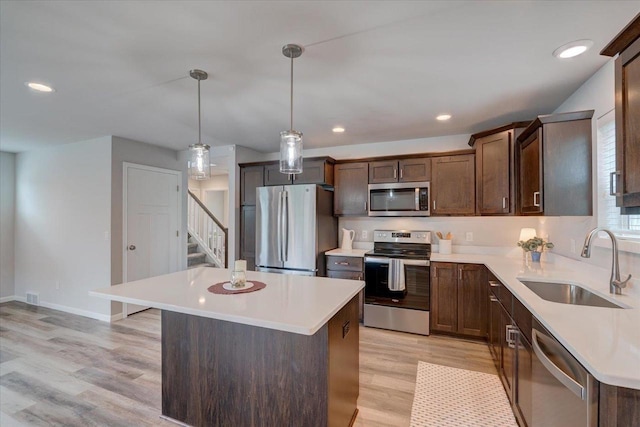 615 Prospect Rd, Waunakee, WI 53597 - kitchen with stainless steel appliances, light countertops, a kitchen island, light wood-style flooring, and pendant lighting