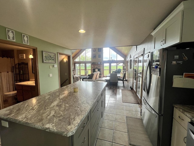 E3577 US Highway 14, Coon Valley, WI 54623 - kitchen with freestanding refrigerator, a center island, light tile patterned floors, light stone countertops, and white cabinetry