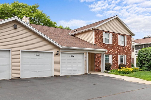 2360 Wisconsin St, Oshkosh, WI 54901 - traditional-style house with a chimney, brick siding, a shingled roof, driveway, and a garage