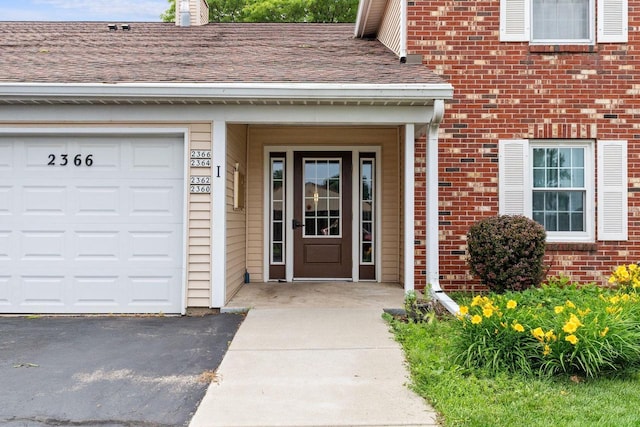 2360 Wisconsin St, Oshkosh, WI 54901 - doorway to property featuring brick siding, asphalt driveway, an attached garage, and roof with shingles