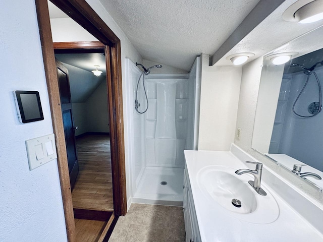 2377 S 76th St, West Allis, WI 53219 - full bathroom featuring a textured ceiling, a shower stall, vanity, lofted ceiling, and tile patterned flooring