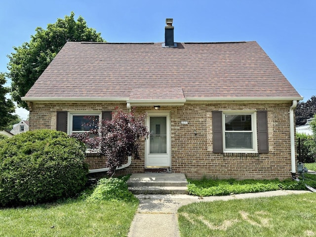 2377 S 76th St, West Allis, WI 53219 - cape cod-style house featuring brick siding, a chimney, roof with shingles, and a front yard