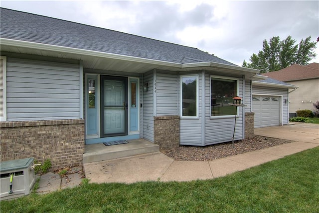 1634 Nicholas Dr, Eau Claire, WI 54703 - view of exterior entry with roof with shingles, brick siding, concrete driveway, and an attached garage