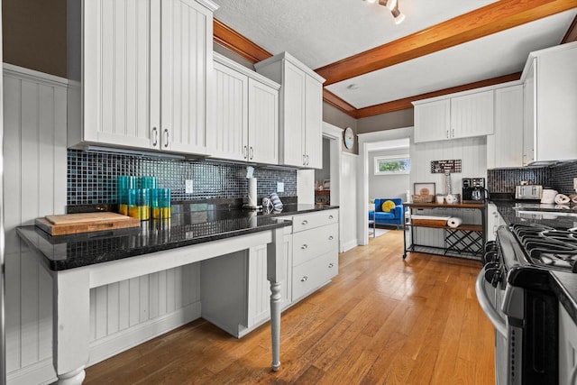 415 S Lake Shore Dr, Lake Geneva, WI 53147 - kitchen with stainless steel gas stove, dark countertops, backsplash, and beamed ceiling