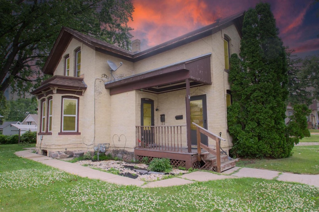 908 E Main St, Watertown, WI 53094 - view of front of home featuring brick siding, a yard, a balcony, and a chimney