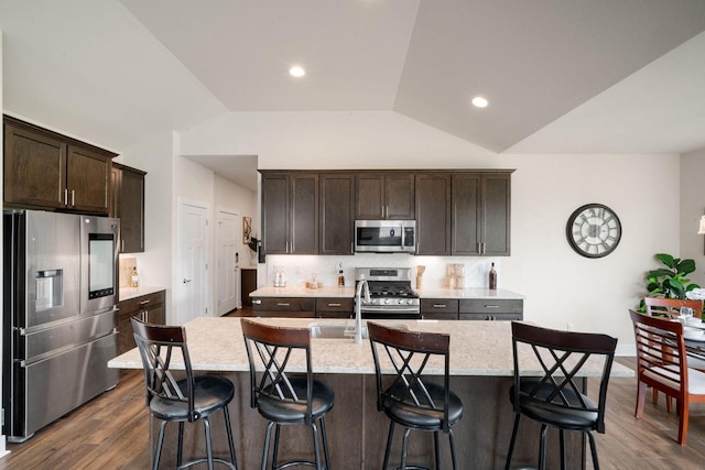 520 Meadow View Dr, Slinger, WI 53086 - kitchen with appliances with stainless steel finishes, dark brown cabinets, an island with sink, backsplash, and lofted ceiling