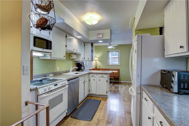 1418 Keith St, Eau Claire, WI 54701 - kitchen featuring white appliances, a peninsula, white cabinets, and backsplash