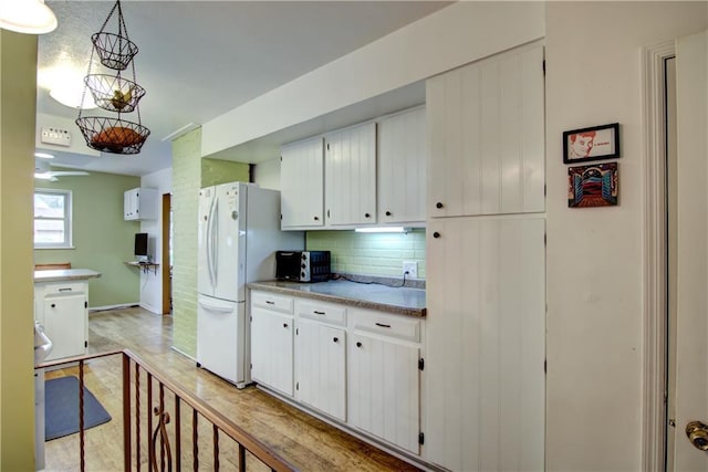 1418 Keith St, Eau Claire, WI 54701 - kitchen featuring freestanding refrigerator, backsplash, white cabinetry, and light countertops