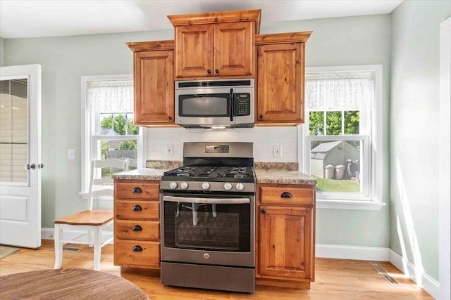 117 6th St, Nekoosa, WI 54457 - kitchen featuring stainless steel appliances, brown cabinets, backsplash, and light wood-type flooring