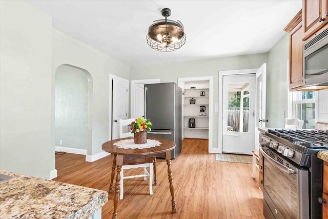 117 6th St, Nekoosa, WI 54457 - kitchen with appliances with stainless steel finishes, arched walkways, light wood-style floors, and brown cabinets