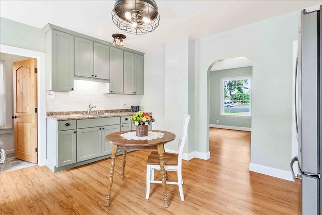 117 6th St, Nekoosa, WI 54457 - kitchen with arched walkways, gray cabinets, freestanding refrigerator, decorative backsplash, and light wood-style floors