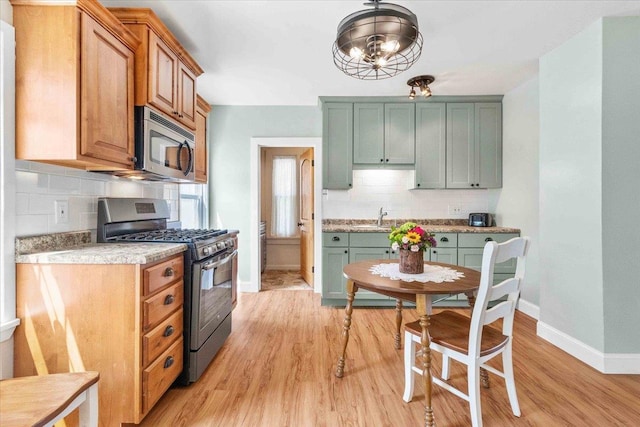 117 6th St, Nekoosa, WI 54457 - kitchen with stainless steel appliances, decorative backsplash, light wood-style flooring, and light countertops