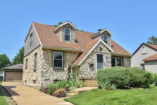 819 S 90th St, West Allis, WI 53214 - view of front of property with stone siding, a front lawn, a garage, a shingled roof, and an outdoor structure