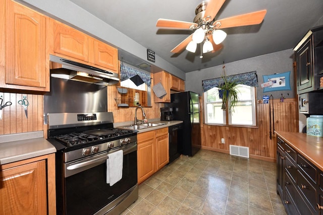 819 S 90th St, West Allis, WI 53214 - kitchen with black appliances, under cabinet range hood, a ceiling fan, light countertops, and wood walls