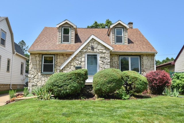 819 S 90th St, West Allis, WI 53214 - view of front facade featuring stone siding, a front yard, a chimney, and a shingled roof