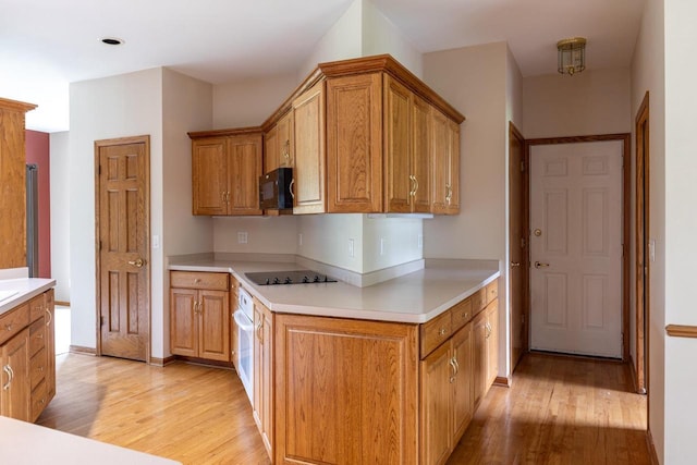 4431 Bellhaven Ln, Oshkosh, WI 54904 - kitchen featuring light wood-style floors, black appliances, light countertops, and brown cabinetry